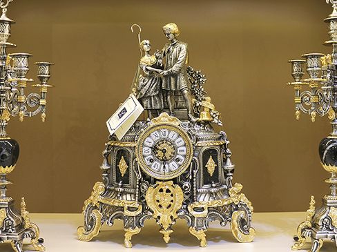 Набор из бронзовых часов и 2 подсвечников, выполненный в золотистом и серебристом цветах. 